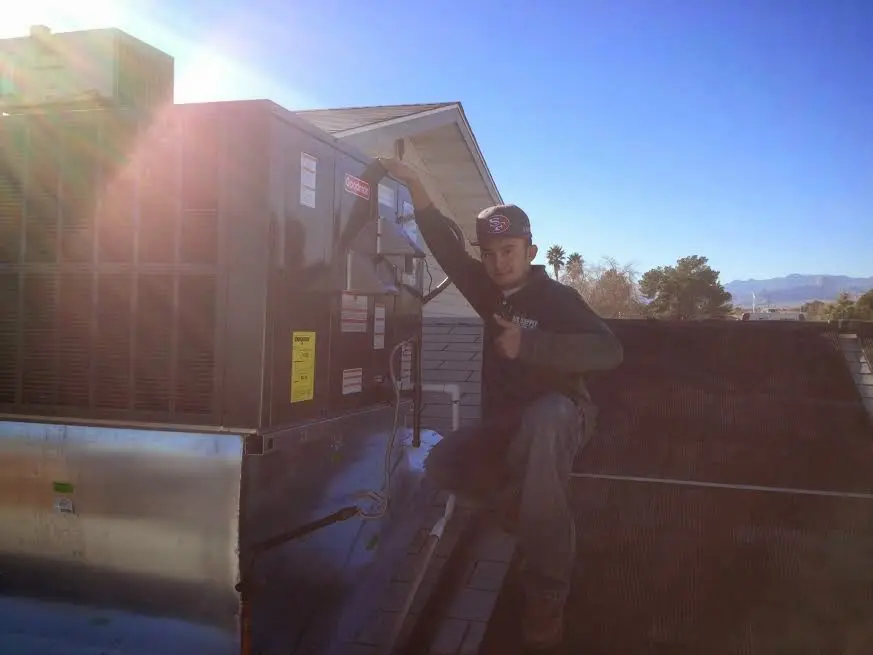 HVAC technician performing AC Tune-Up on a rooftop unit in Bryan